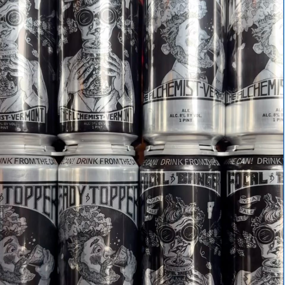 Rows of The Alchemist Vermont beer cans feature black-and-white illustrations of bearded figures drinking ale.